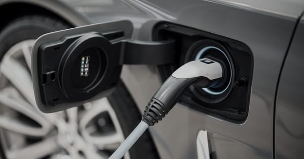  A close-up shot of a grey electric vehicle plugged into a charging station in Canada
